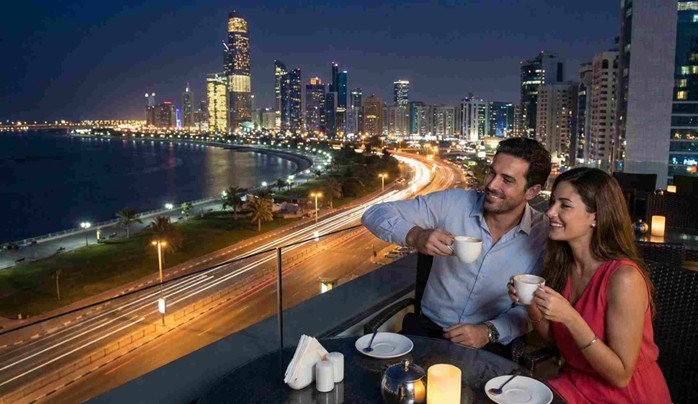 A traveler admiring the illuminated skyline and the glowing Sheikh Zayed Grand Mosque during a magical Abu Dhabi Layover Tour at Night.