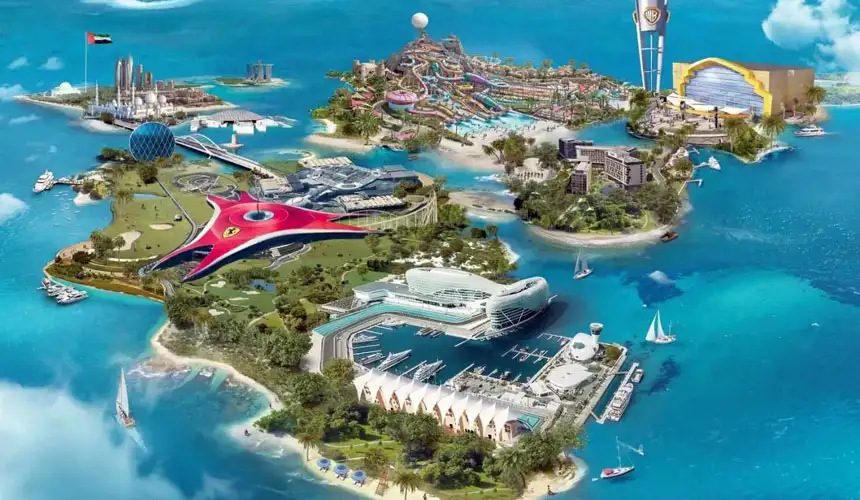 Aerial panoramic view of Yas Island in Abu Dhabi showing Ferrari World, theme park islands, water attractions, hotels, and turquoise sea with the iconic red Ferrari structure.